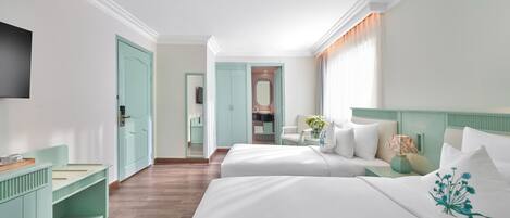A hotel room with two beds, a TV, a desk, and a bathroom visible through an open door.