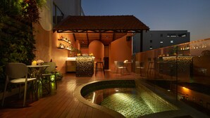 Un bar situé sur le toit d’un immeuble, avec une piscine, des places assises en plein air et un mur en pierre.