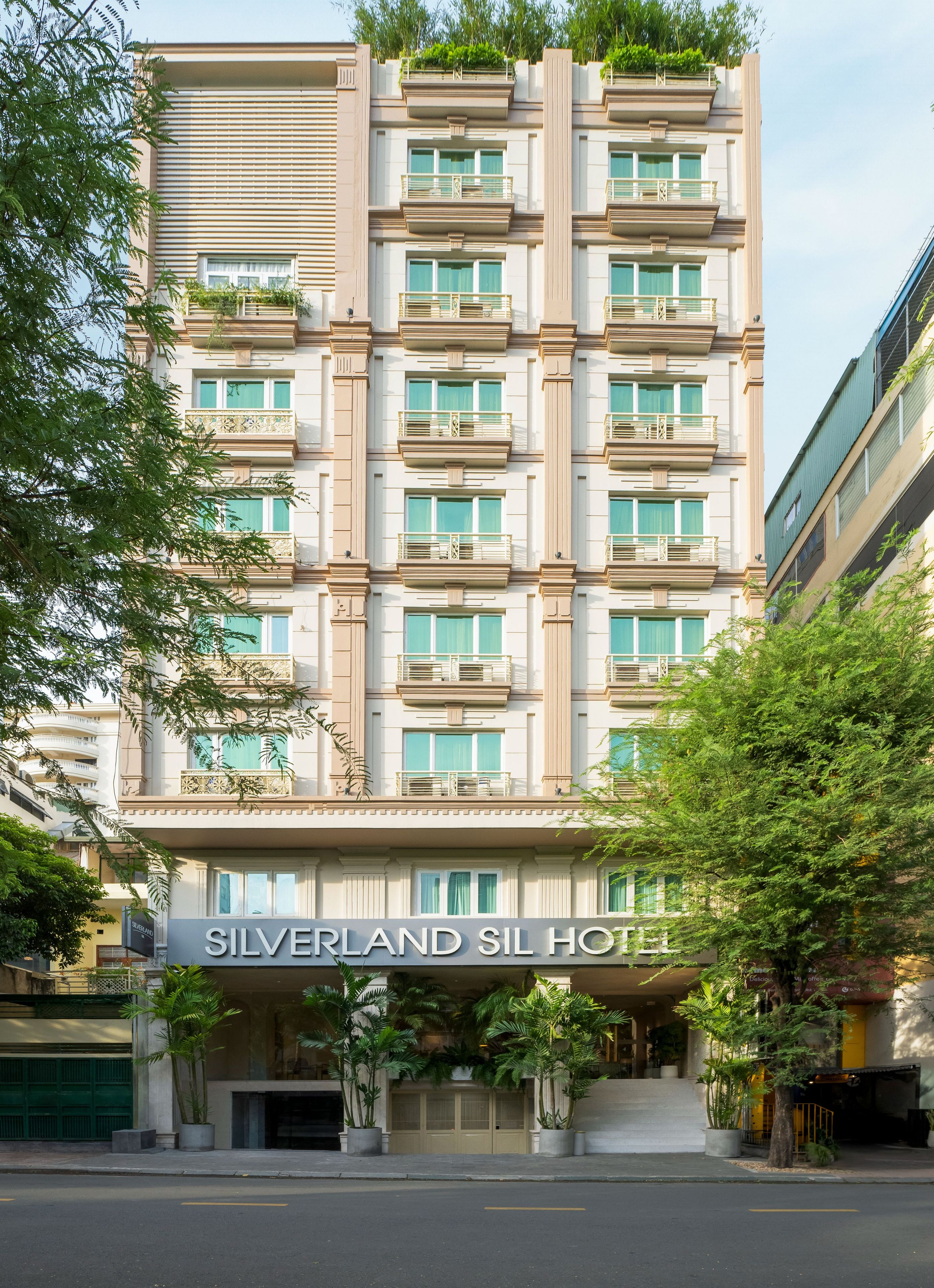Un hôtel à plusieurs étages, doté d’une façade moderne, de balcons et d’une enseigne indiquant « SILVERLAND SIL HOTEL ».