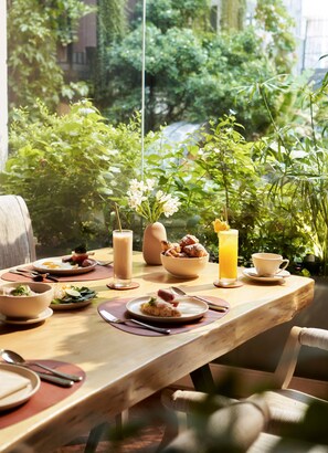 A dining table set with various dishes, a tall glass of orange juice, and a vase with flowers. - Silverland Sil Hotel (Ho Chi Minh City)