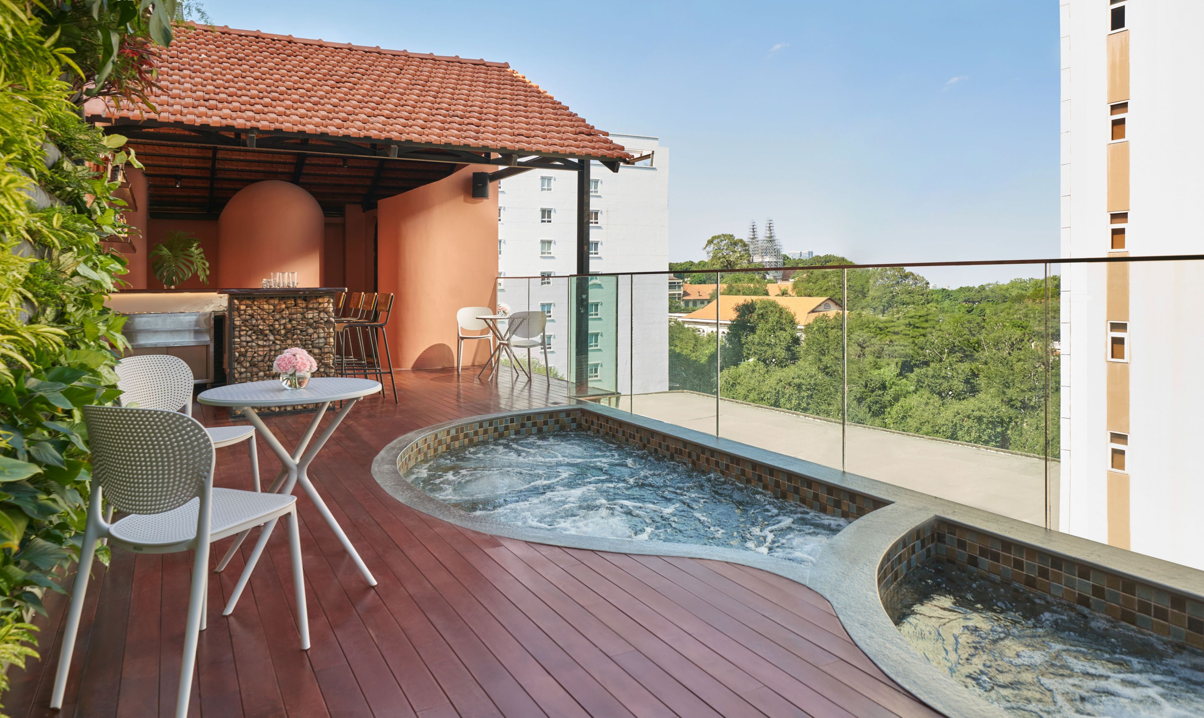 En tagterrasse med jacuzzi, udendørs møbler og udsigt over byen.