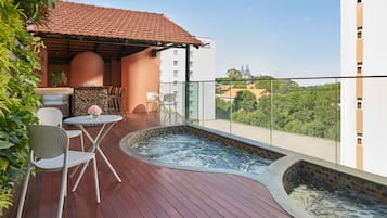 En tagterrasse med jacuzzi, udendørs møbler og udsigt over byen.