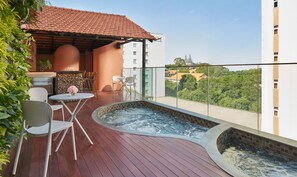 Eine Dachterrasse mit Whirlpool, Sitzgelegenheiten im Freien und Blick auf die Stadt.