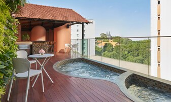 A rooftop terrace with a hot tub, outdoor seating, and a view of the city.
