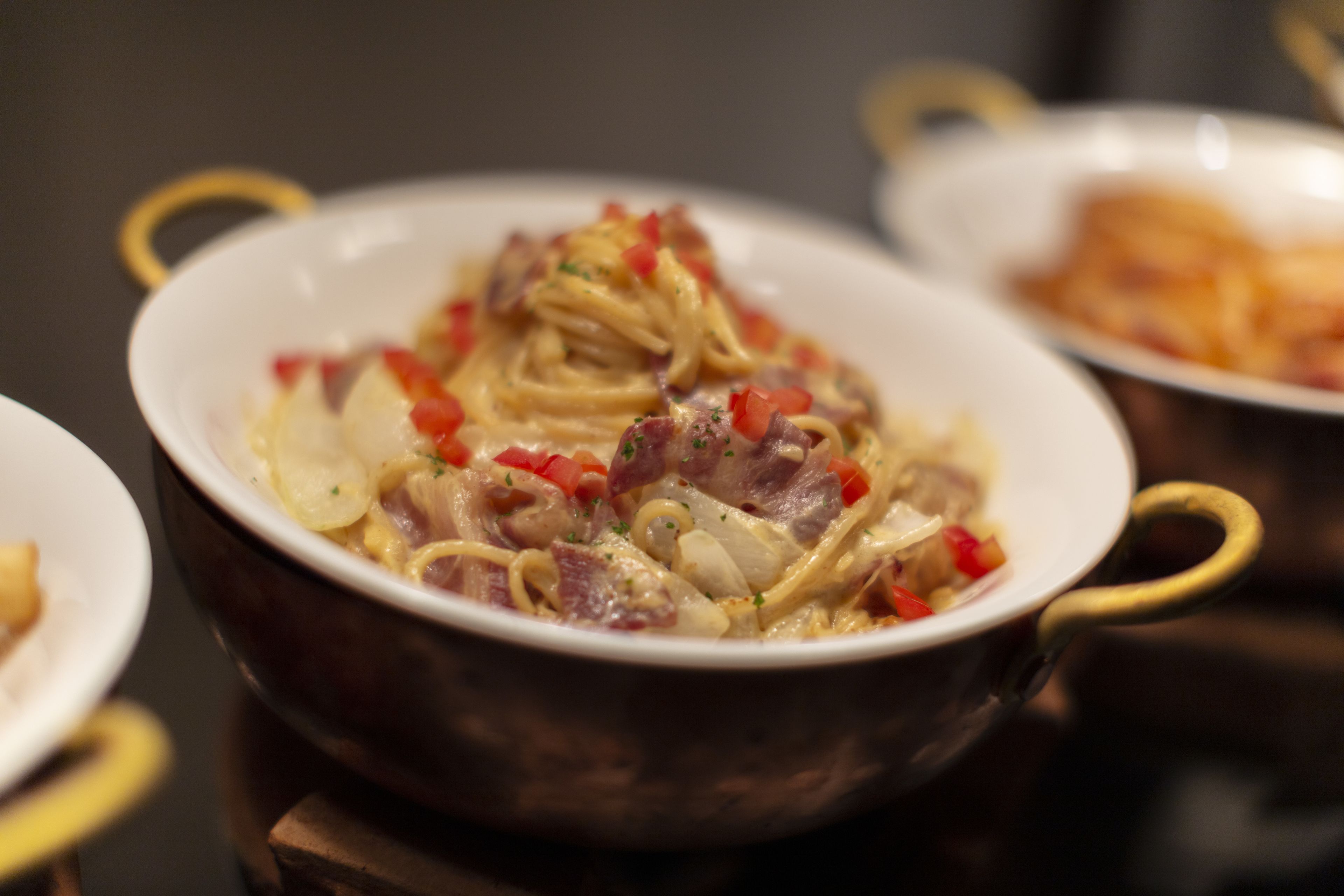 Primer plano de un plato con fideos, carne y pimientos rojos en un bol.