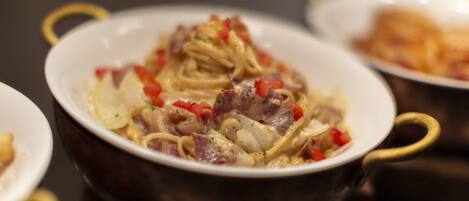 Primer plano de un plato con fideos, carne y pimientos rojos en un bol.
