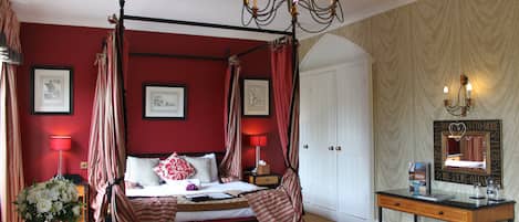 Un lit à baldaquin, une table de chevet avec une lampe et un miroir au mur.
