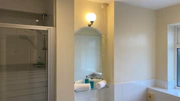 A modern bathroom with a glass shower enclosure, a large mirror, and a built-in sink with a vanity.