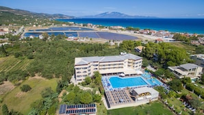 A hotel with a large pool, multiple balconies, and a view of the sea. - Koukounaria Hotel & Suites (Zakynthos)