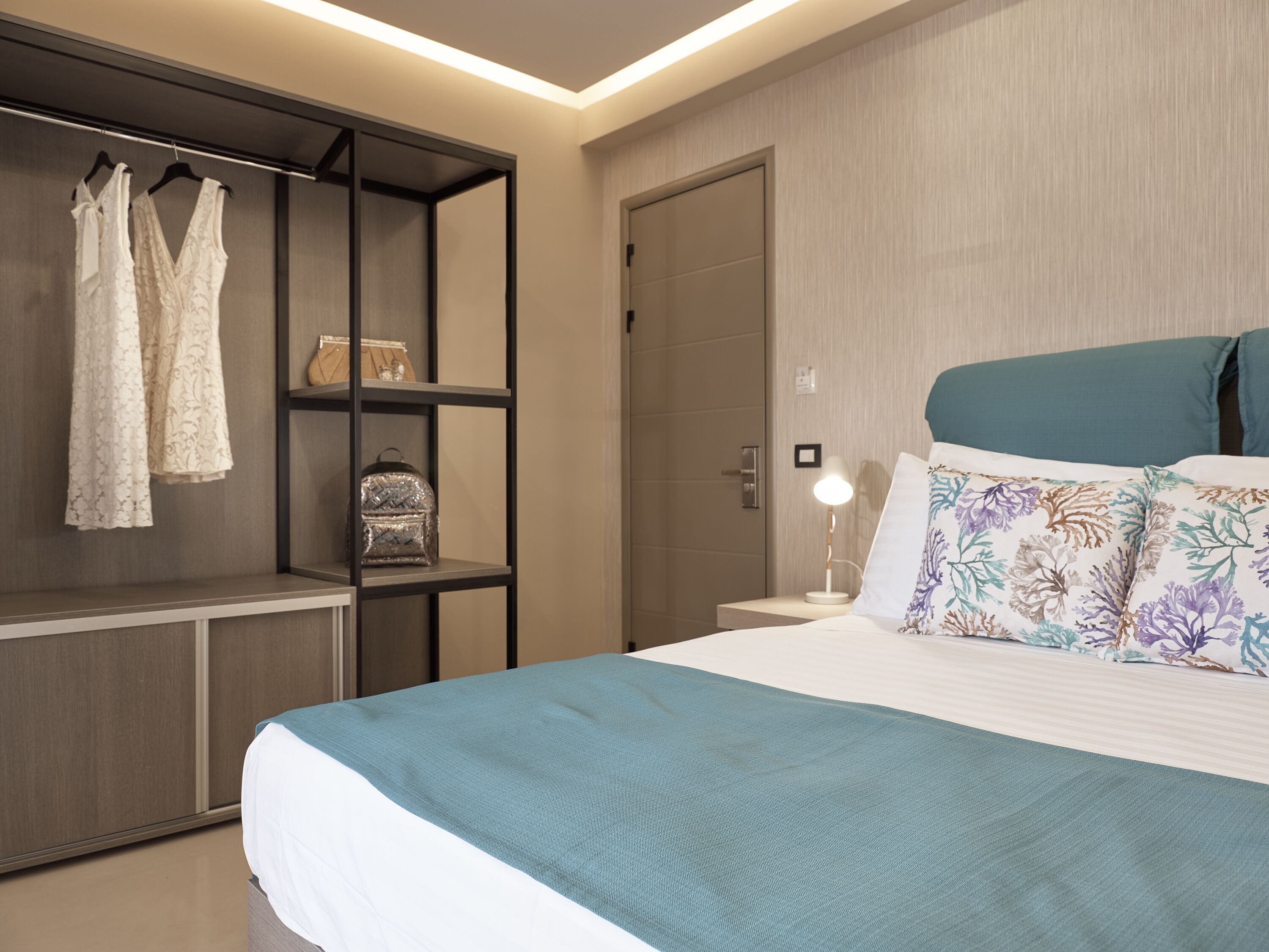 Una habitación de hotel con una cama, un armario y una mesita de noche.