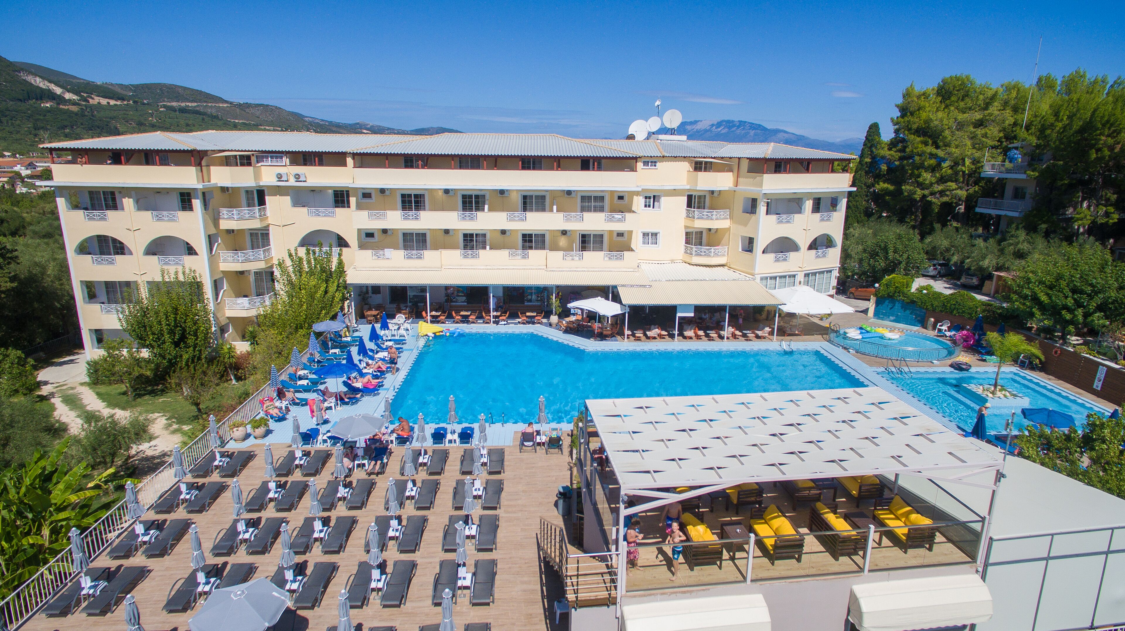 Un hotel con diverse piscine, lettini prendisole e un'ampia area pranzo all'aperto.