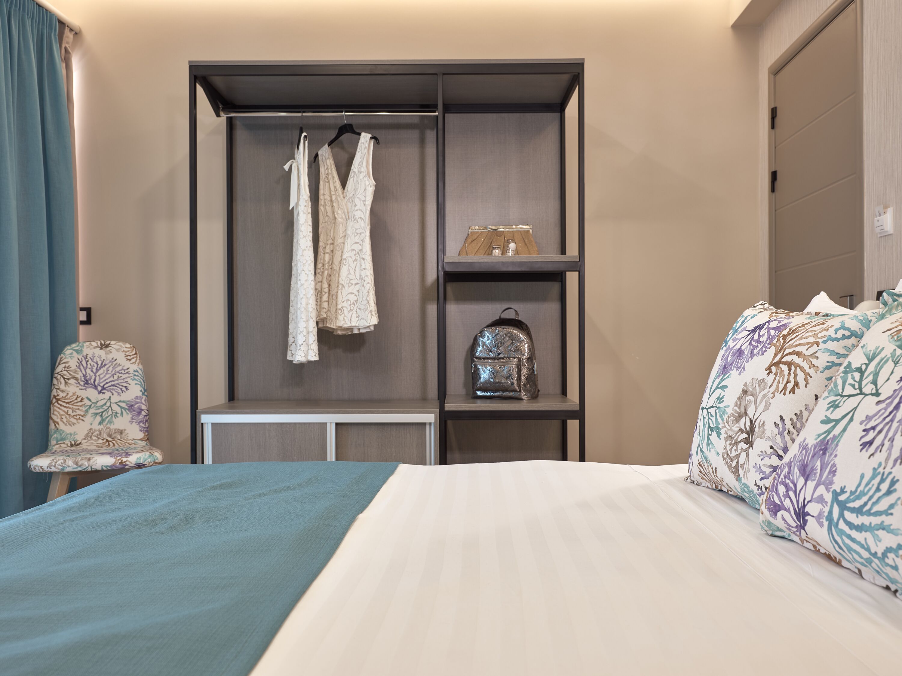 Una habitación de hotel con una cama, un armario, una silla y una mesita.