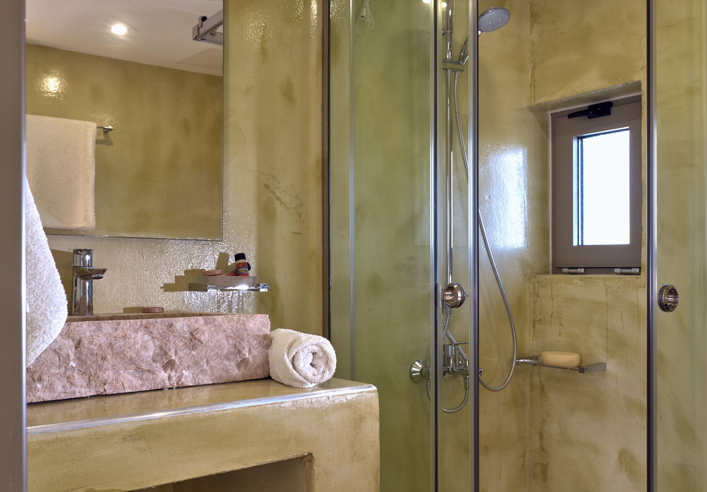 A bathroom with a glass-enclosed shower, a vanity with a marble countertop, and a towel on the counter.