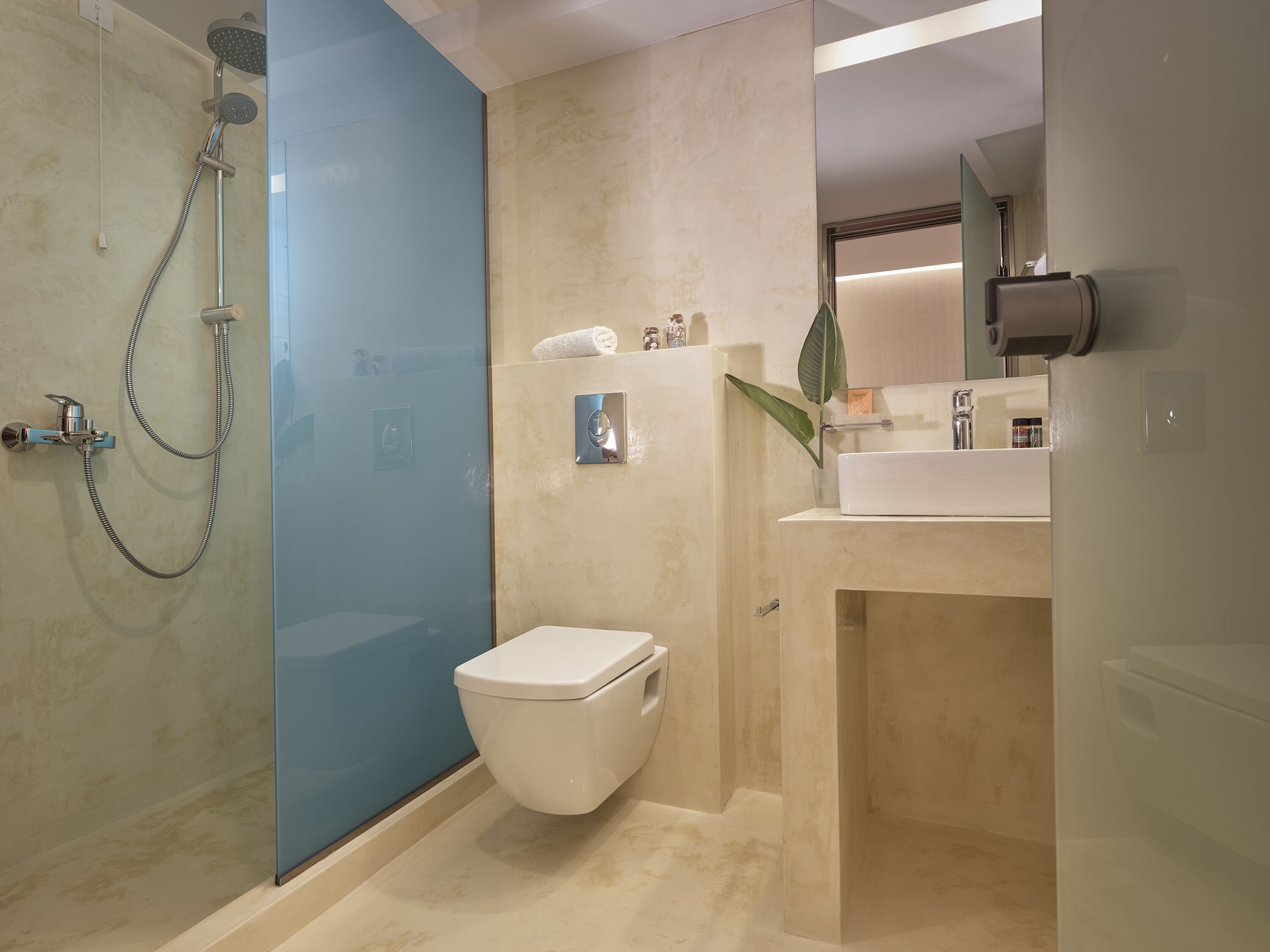 A modern bathroom with a glass shower enclosure, a toilet, and a sink with a mirror above.
