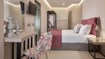 Ein modernes Hotelzimmer mit Bett, Nachttisch, Sessel und einem an der Wand befestigten Fernseher.