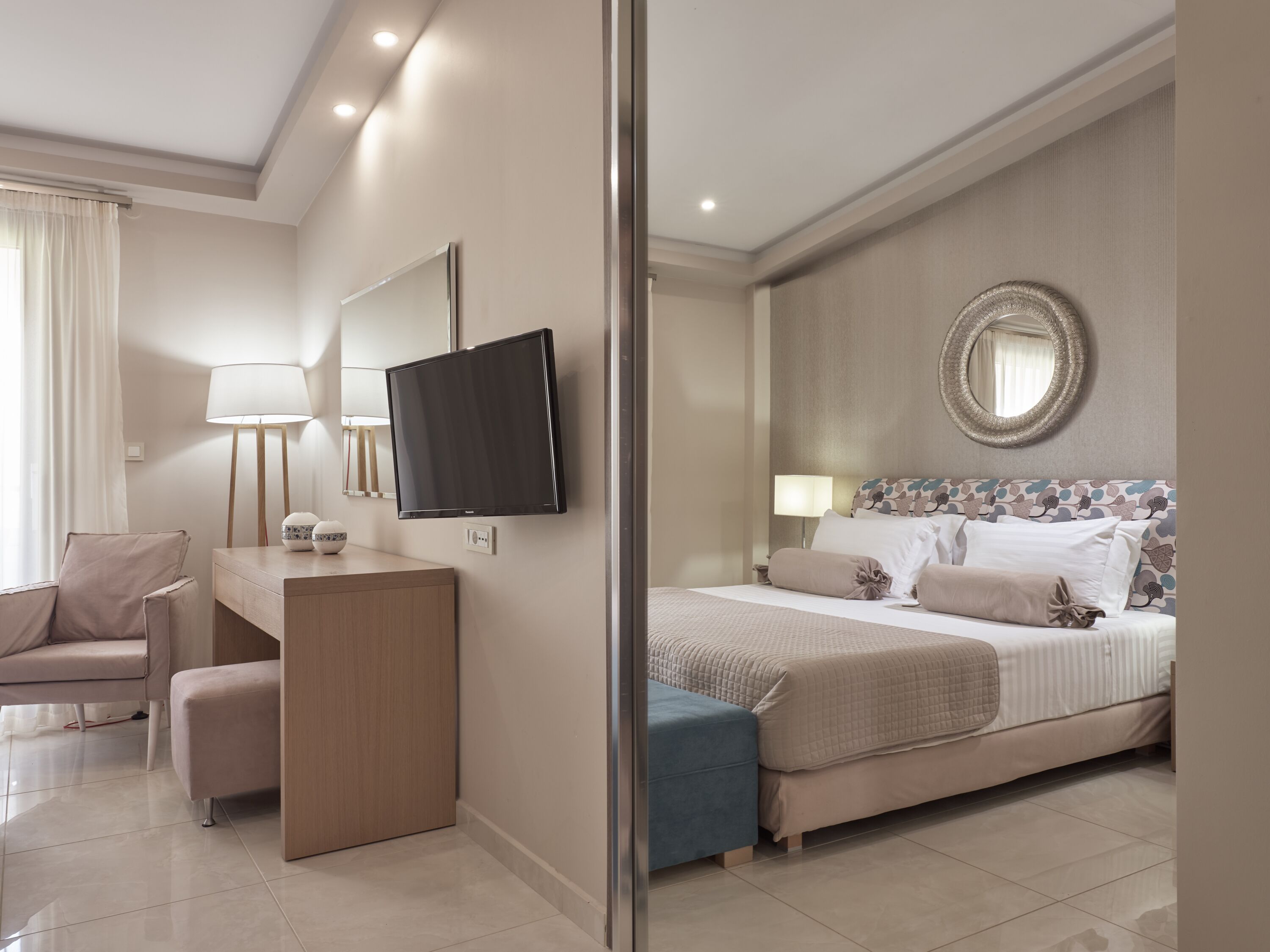 Una habitación de hotel moderna con cama, escritorio, silla, televisor y espejo.
