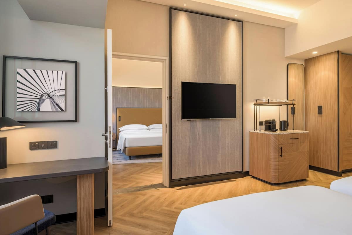 Een hotelkamer met een bed, bureau, televisie, kast en een schilderij aan de muur.