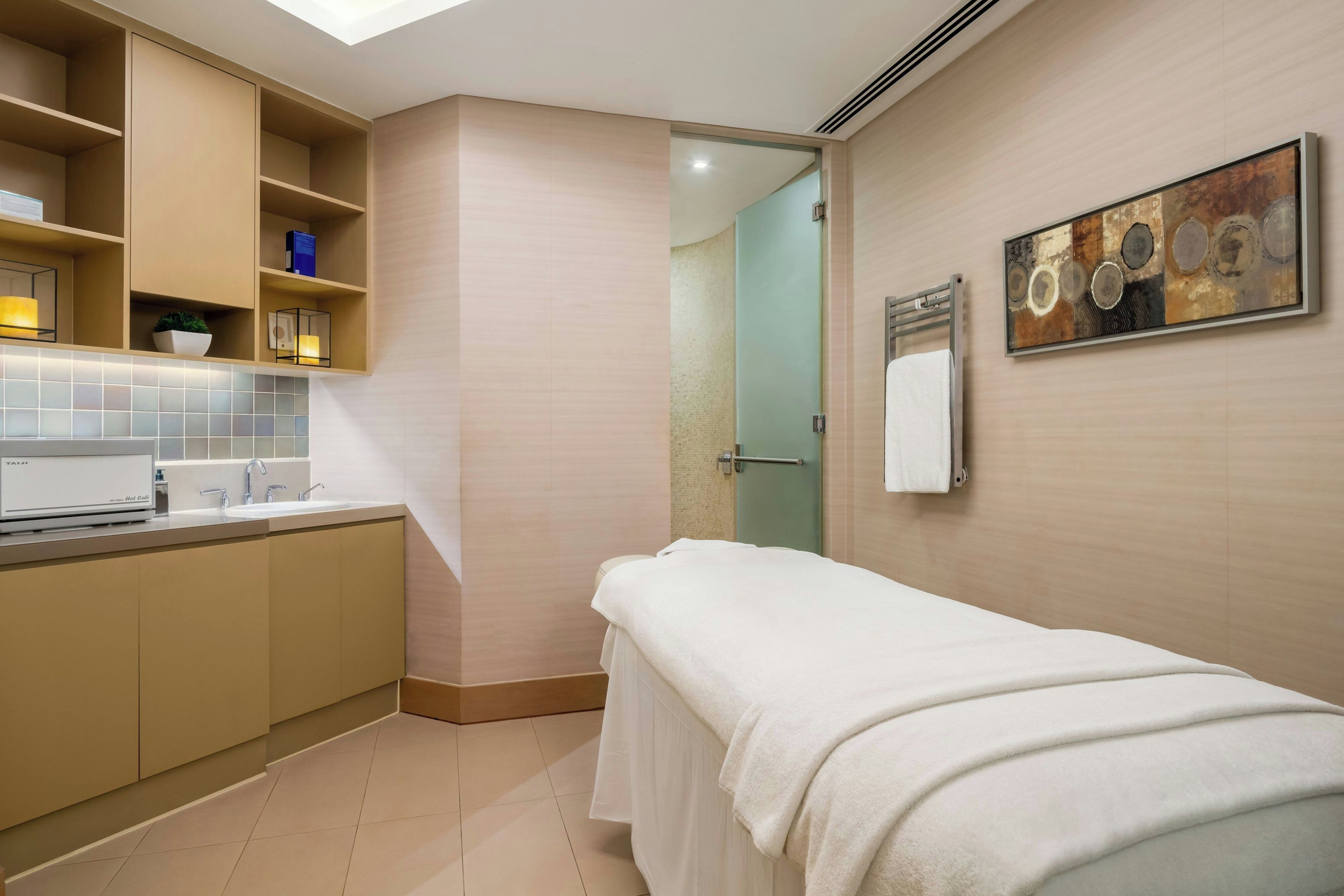 A modern bathroom with a towel-covered bench, a sink, and a shower area.