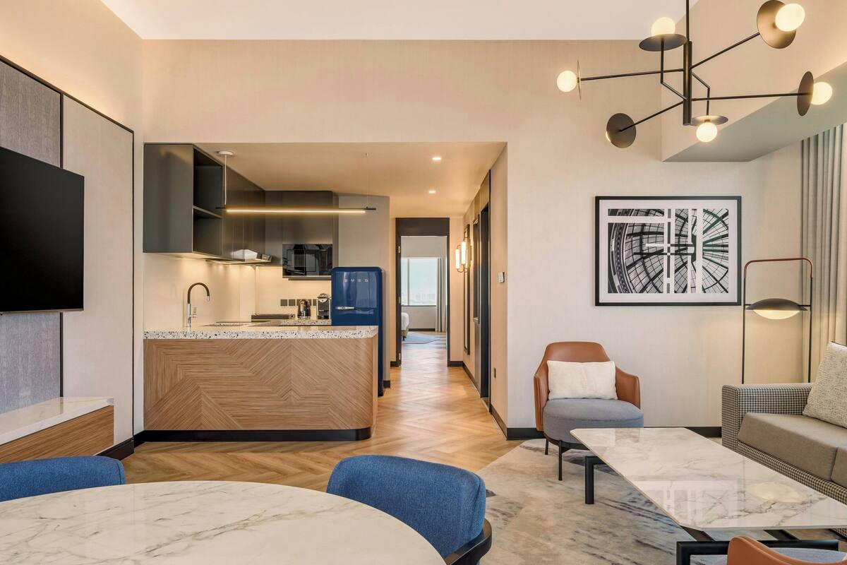 Een moderne hotelkamer met een keukenhoek, een eettafel en een zithoek.