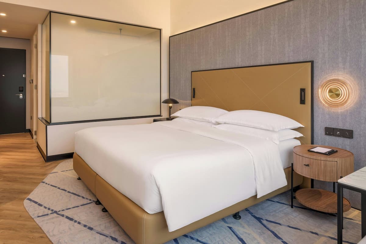 Een moderne hotelkamer met een groot bed, een nachtkastje, een inbouwkleerkast en een wandlamp.