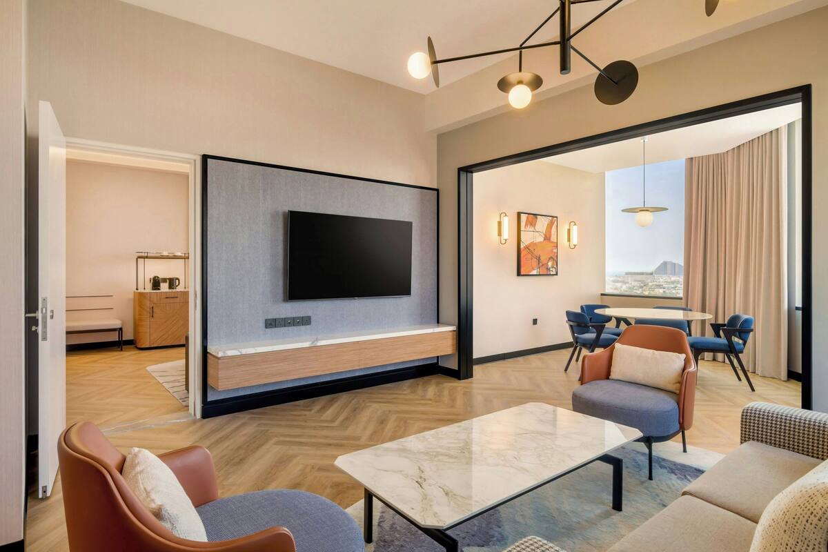 Een moderne hotelkamer met een flatscreen-tv, zithoek en uitzicht op de stad.
