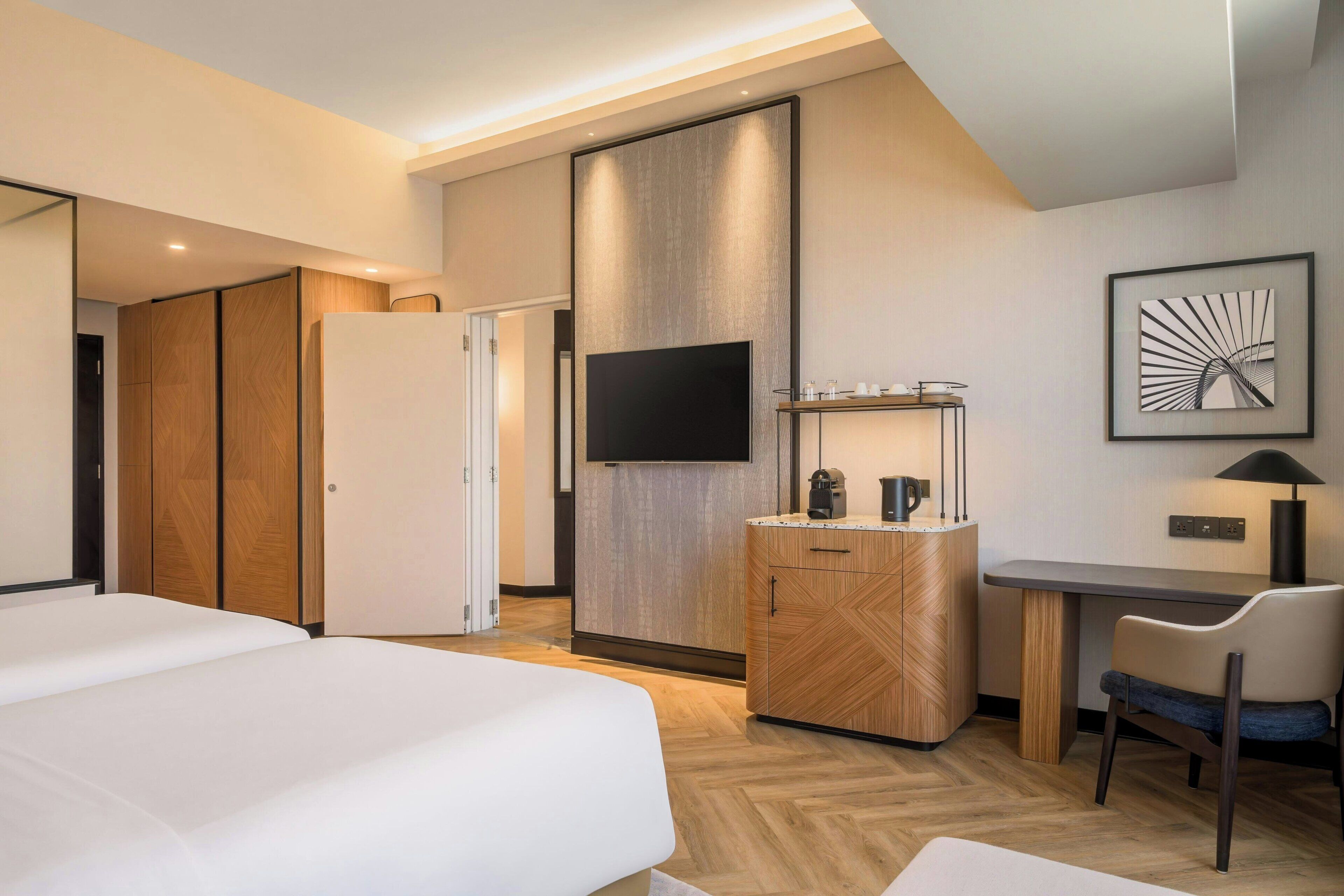 Une chambre d’hôtel moderne équipée d’un lit, d’un bureau, d’une télévision et d’une armoire.