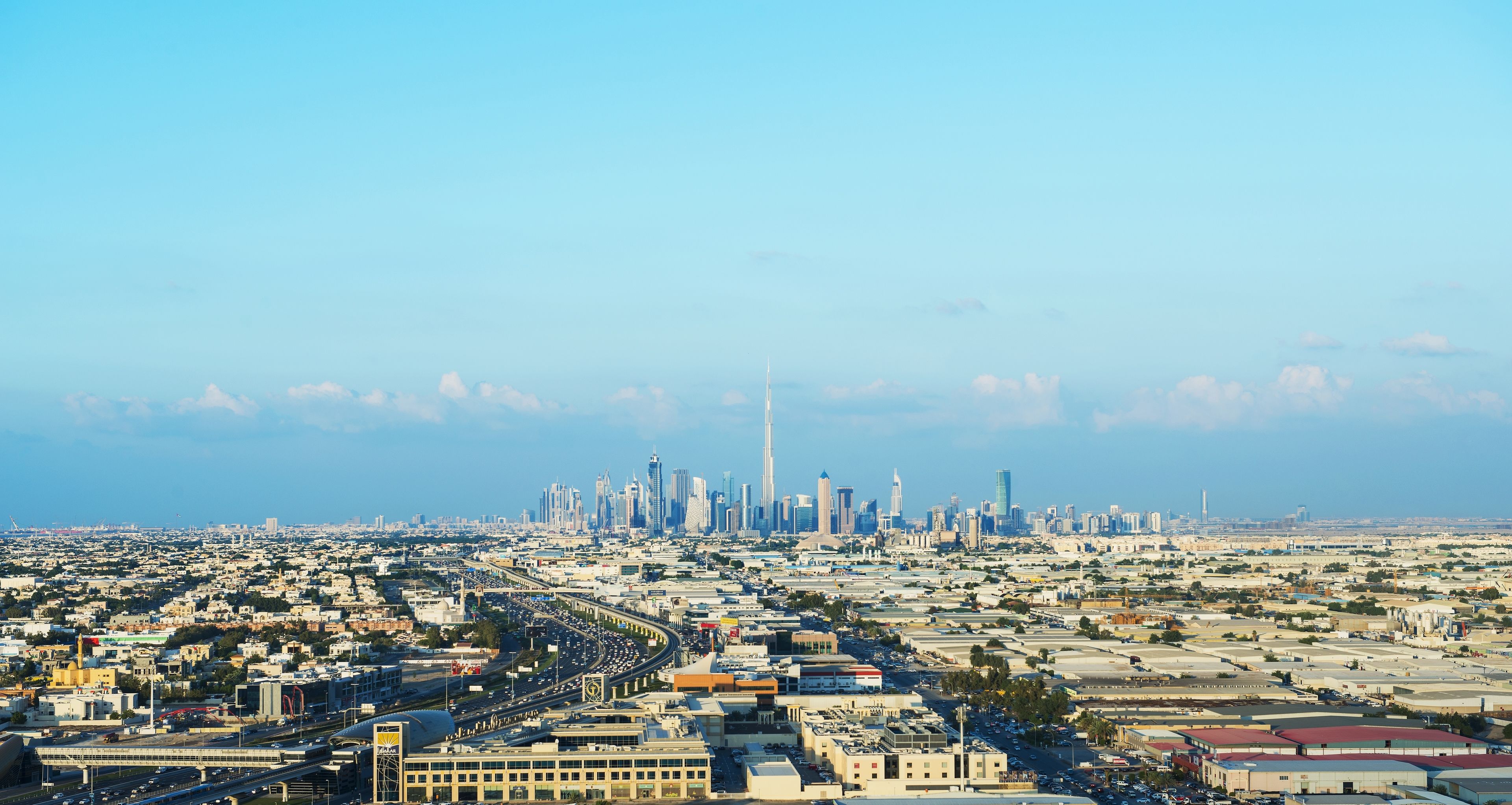 A cityscape with a prominent skyscraper, wide roads, and a mix of commercial and residential buildings.