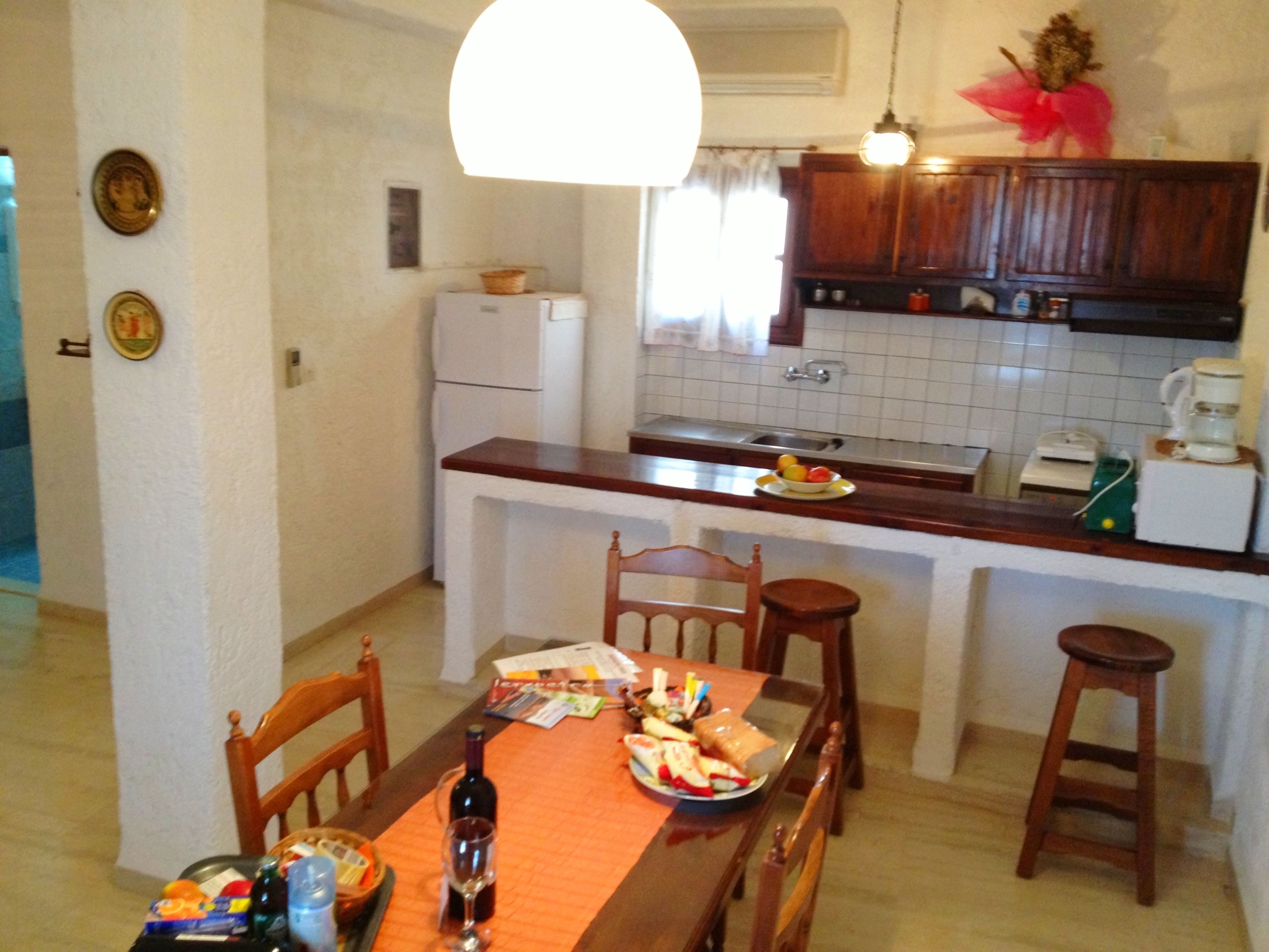 Una cucina compatta con tavolo, sedie e frigorifero.