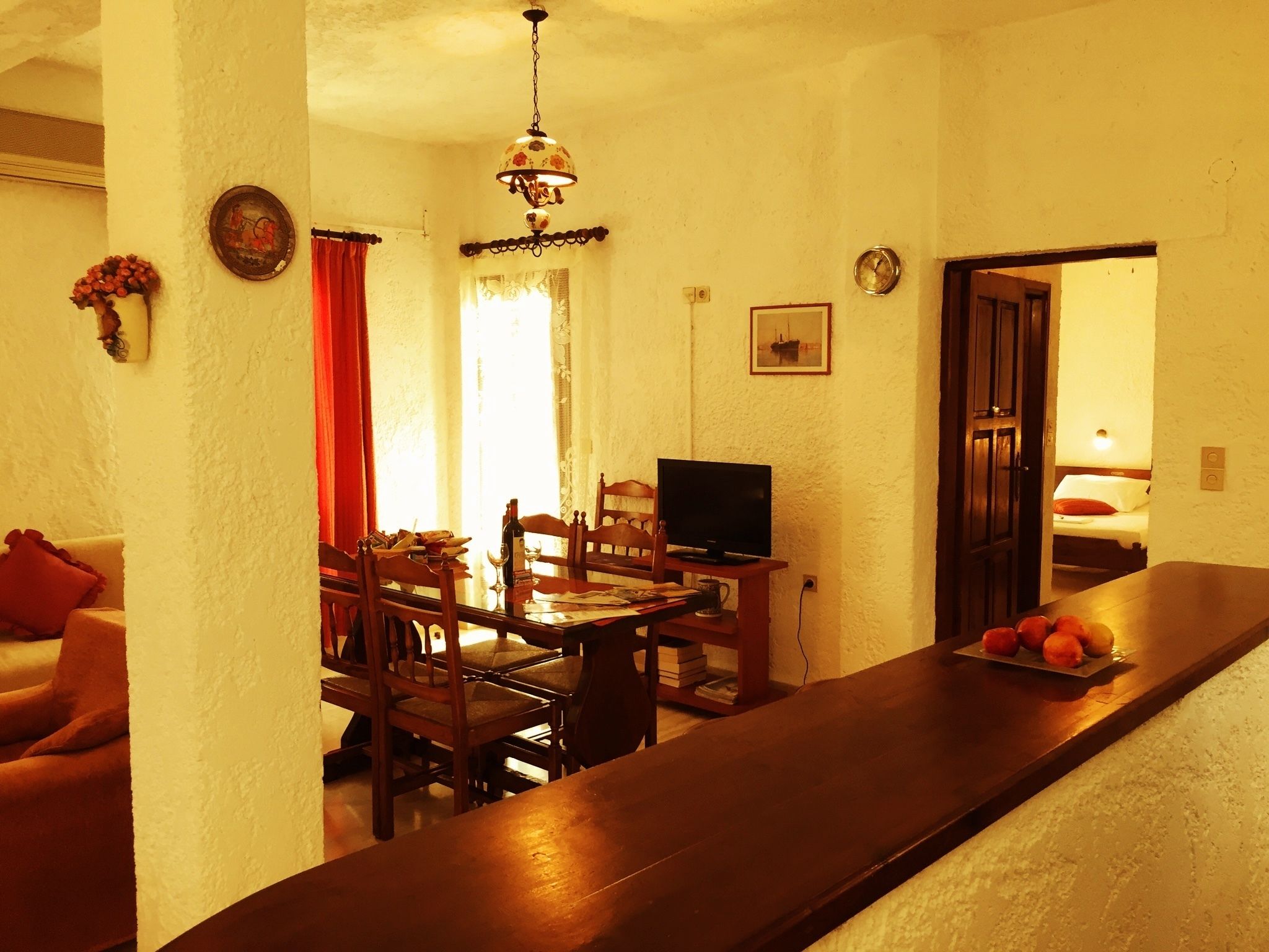 A dining area with a wooden table and chairs, a television, and a red curtain.