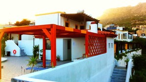 Un edificio moderno con una decoración en rojo y blanco, que presenta un área exterior cubierta con piscina, escaleras y plantas en macetas.