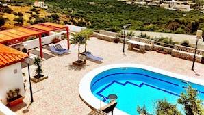 Piscina en la azotea con vista al mar, sillas de descanso y un área de estar cubierta.