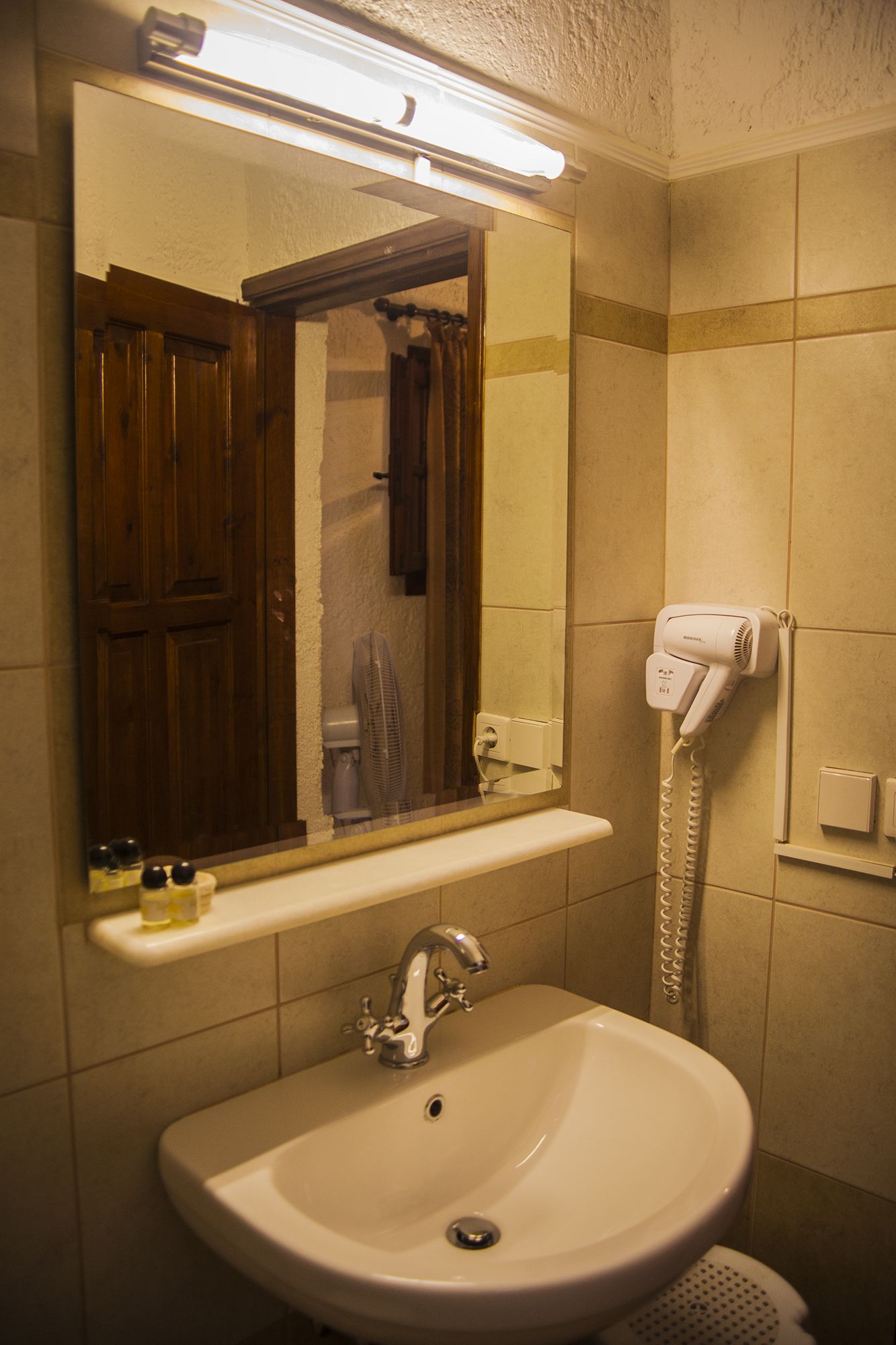 A bathroom with a sink, mirror, and hairdryer.