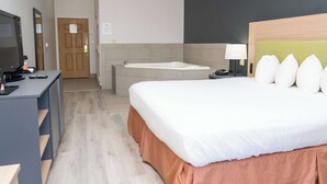A hotel room with a bed, a desk, a television, a bathroom with a bathtub, and a door. - Country Inn & Suites by Radisson, College Station, TX (College Station)