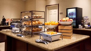 A hotel breakfast area with a self-serve station, a refrigerator, and a variety of food options. - Country Inn & Suites by Radisson, College Station, TX (College Station)