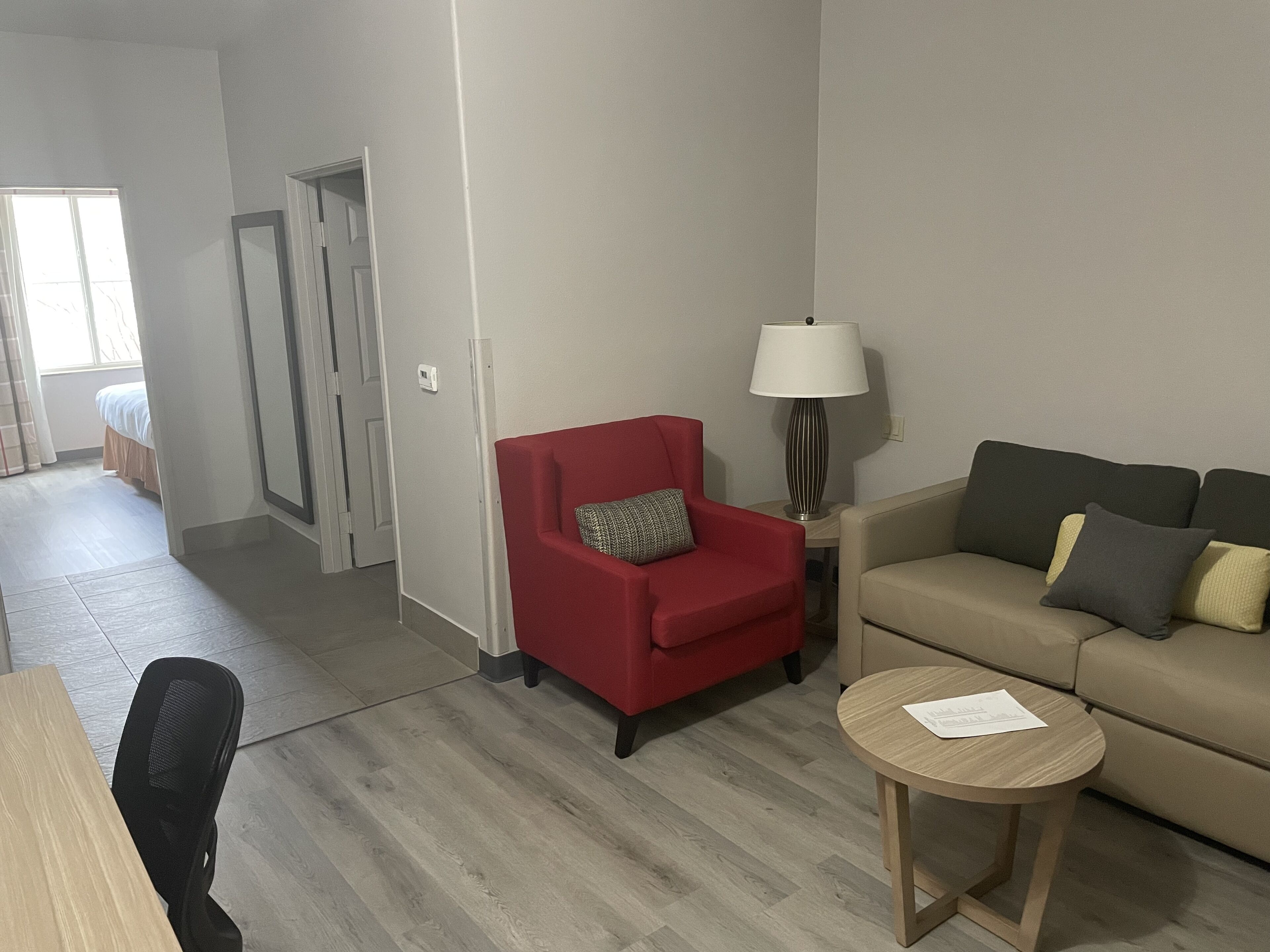 A modern living room with a red armchair, a beige sofa, and a wooden coffee table.