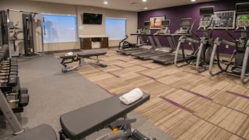 A gym with treadmills, weight machines, and a bench.