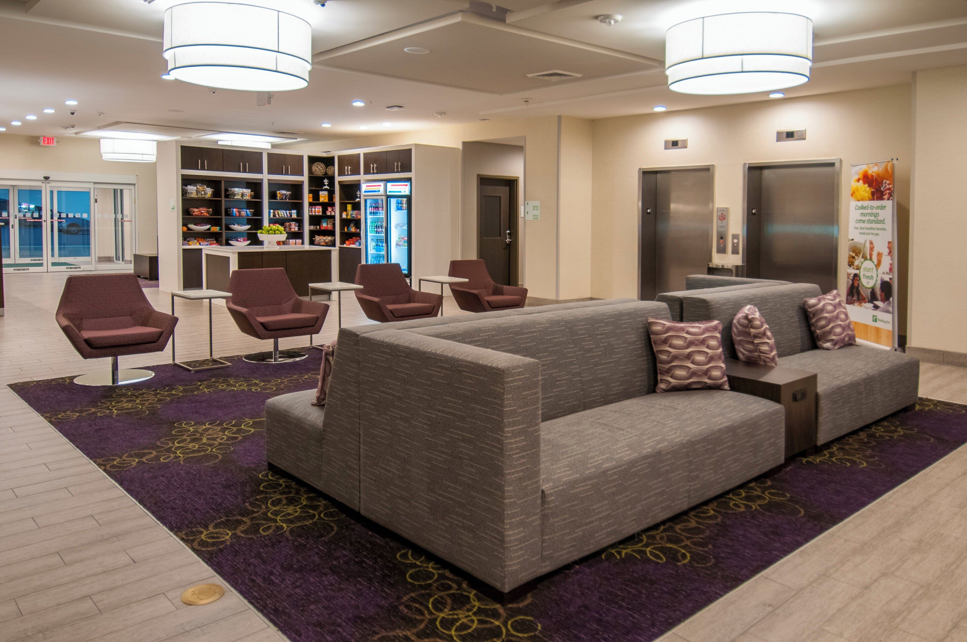 Een hotel lobby met een zithoek, automaten en een plek voor verfrissingen.
