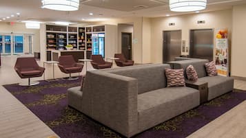 Een hotel lobby met een zithoek, automaten en een plek voor verfrissingen.