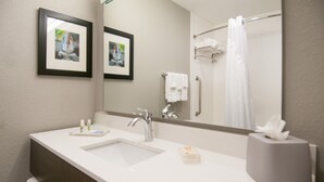 Un baño con un lavamanos blanco, un espejo y un perchero para toallas.