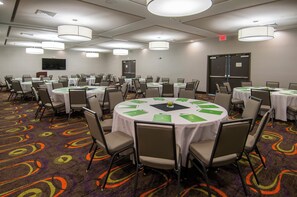 Un salón de conferencias con varias mesas y sillas, equipado con tarjetas de identificación y carpetas, dentro de un hotel.