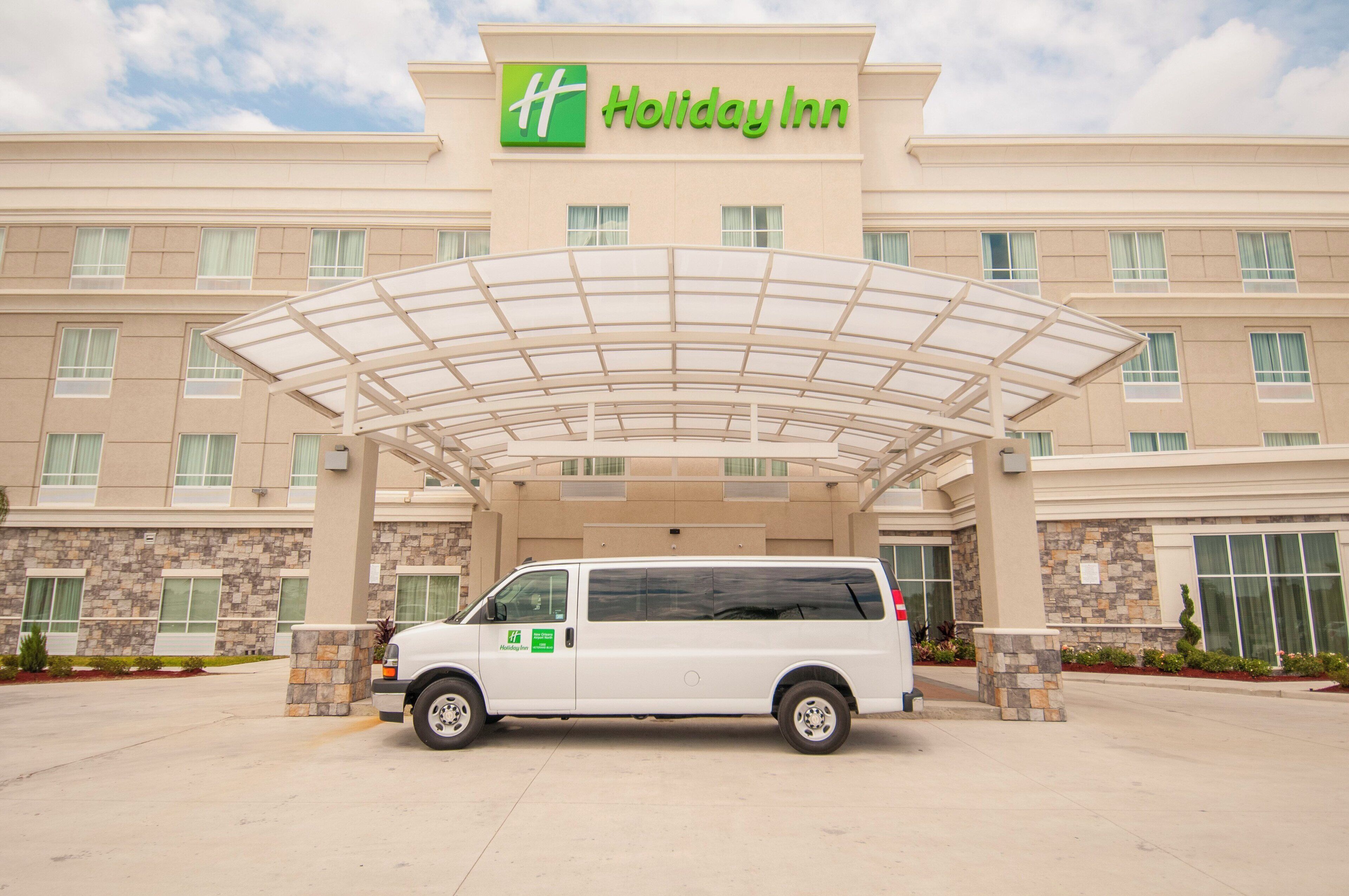 A Holiday Inn hotel with a covered entrance and a white van parked in front.