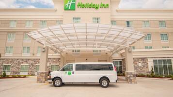 A Holiday Inn hotel with a covered entrance and a white van parked in front.