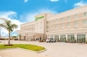 Et Holiday Inn hotel med overdækket indgang, flere etager og parkeringsplads.