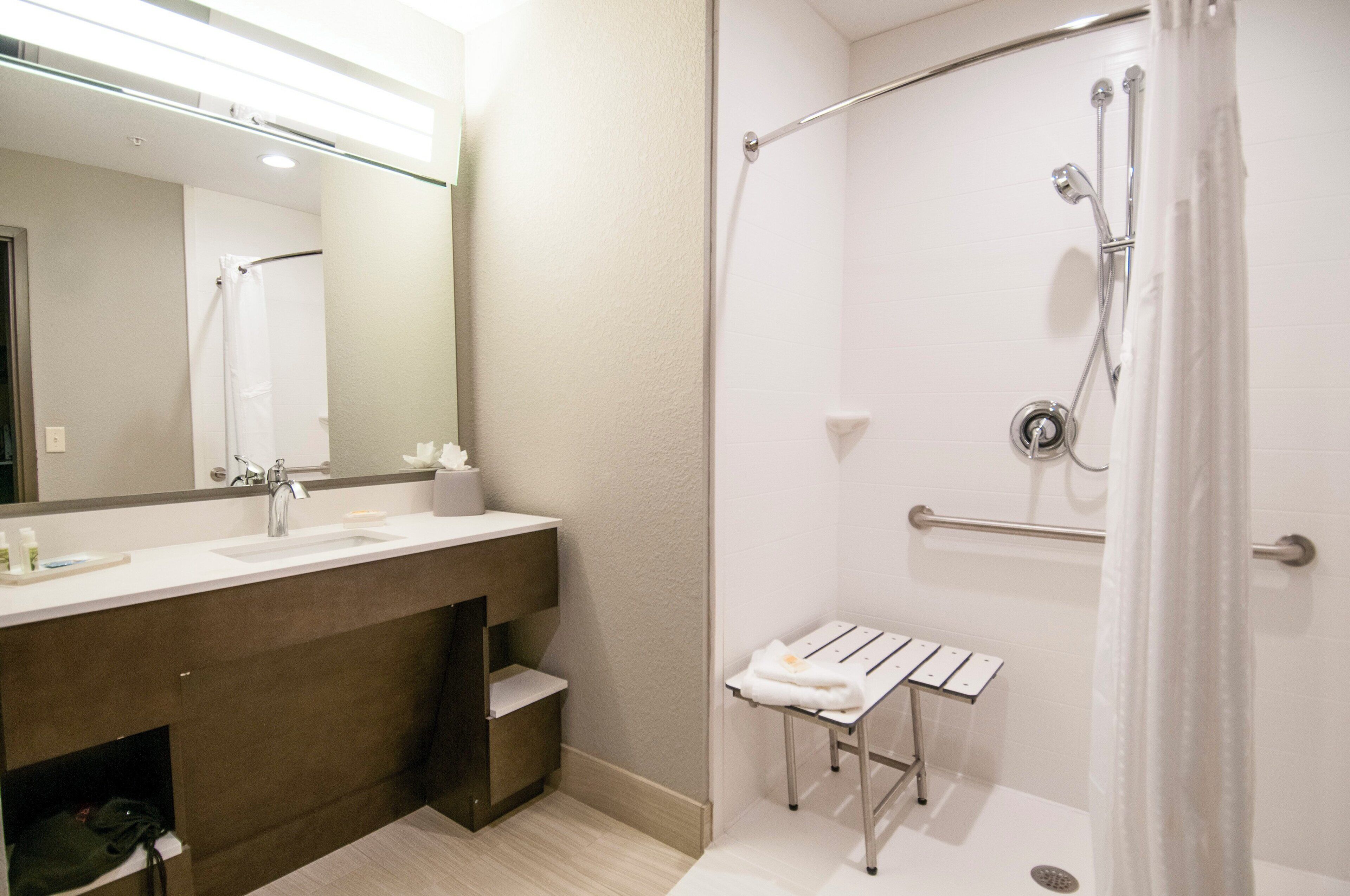 A bathroom with a shower, a sink, and a mirror.