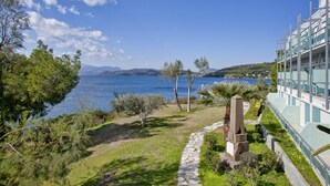 A coastal hotel with a stone pathway leading to a terrace overlooking the sea. - Xenia Poros Image Hotel (Poros)