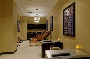 Un cuarto de spa con sillones de masaje, un mostrador de recepción y un cuadro grande en la pared.