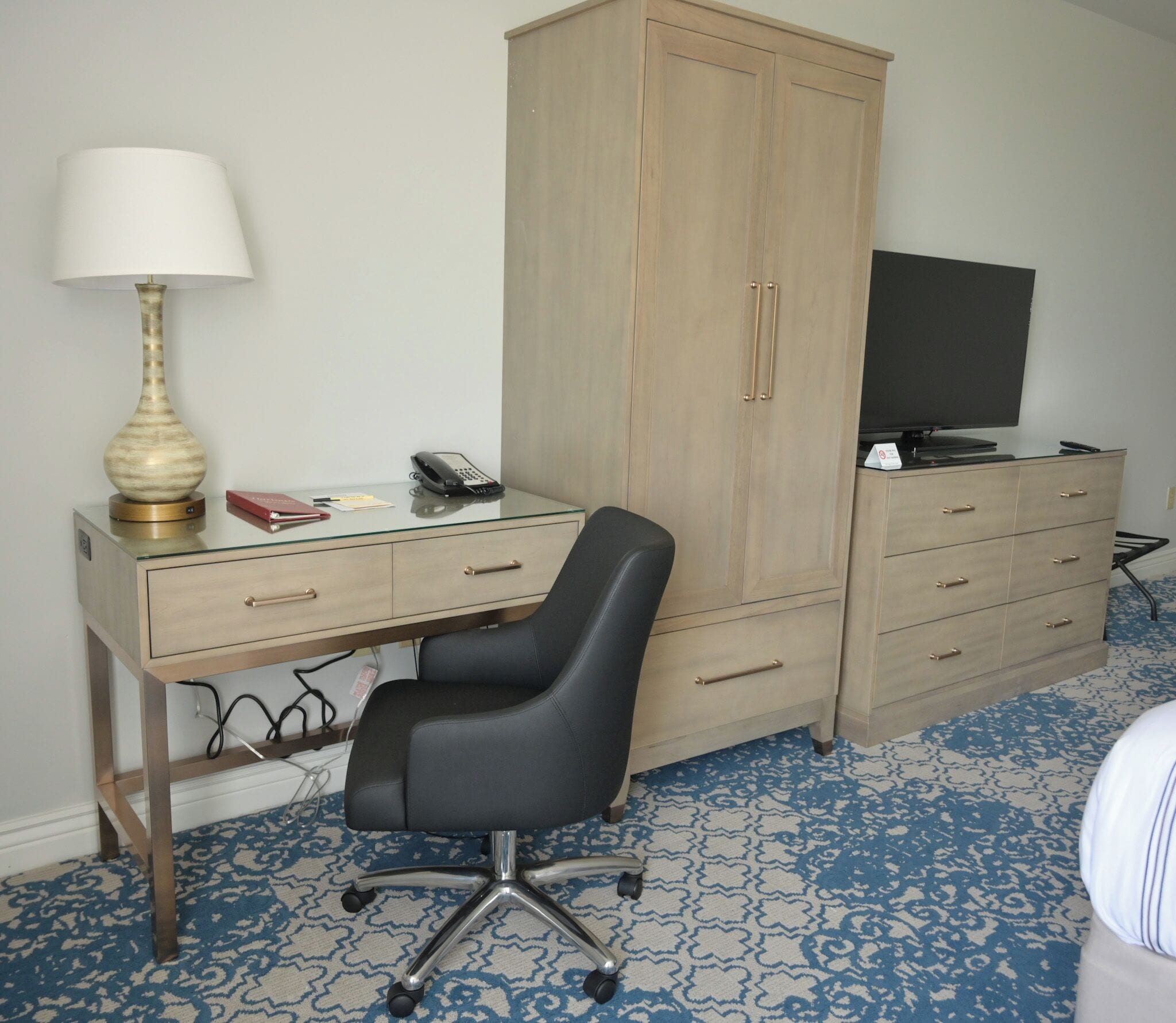 Ett hotellrum med skrivbord, stol, tv och garderob.