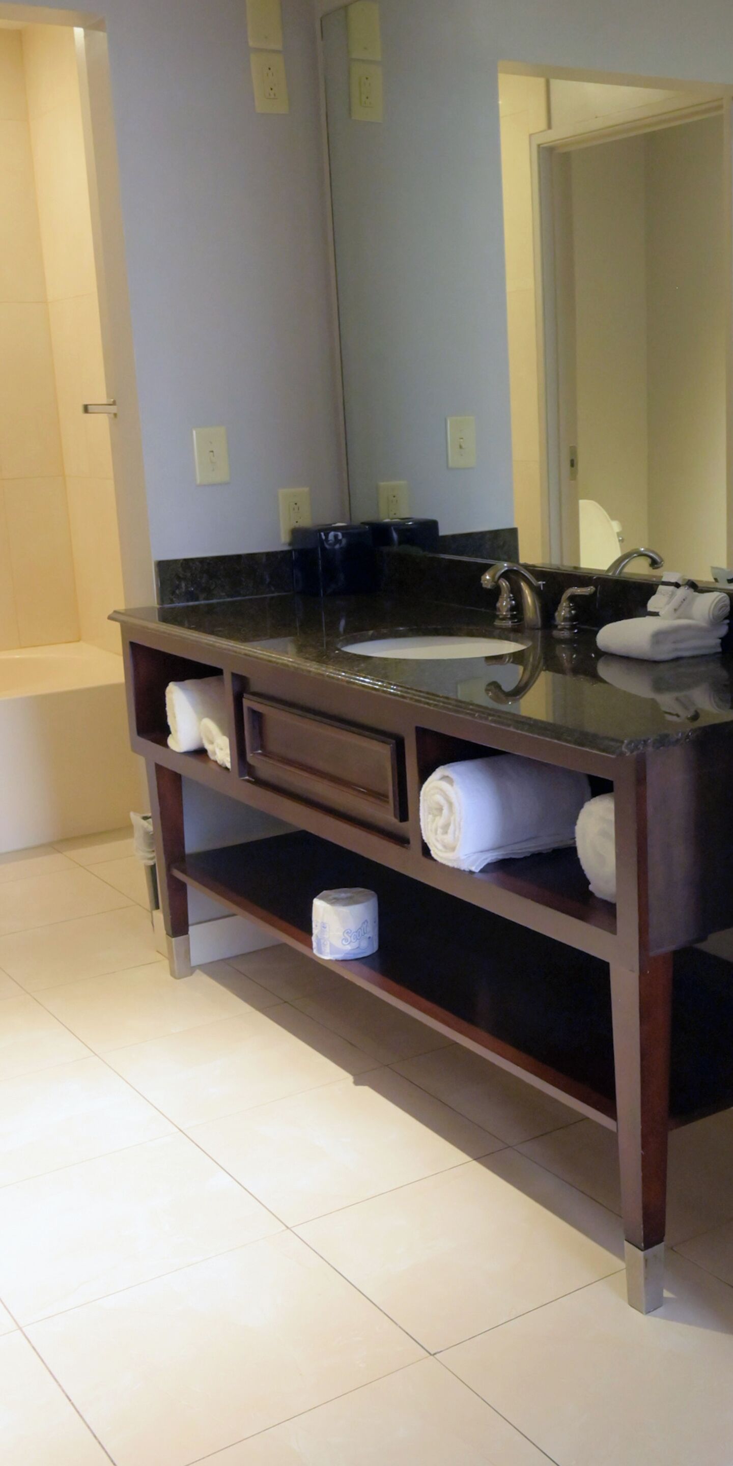 A bathroom with a dark wooden vanity, a large mirror, and a bathtub.