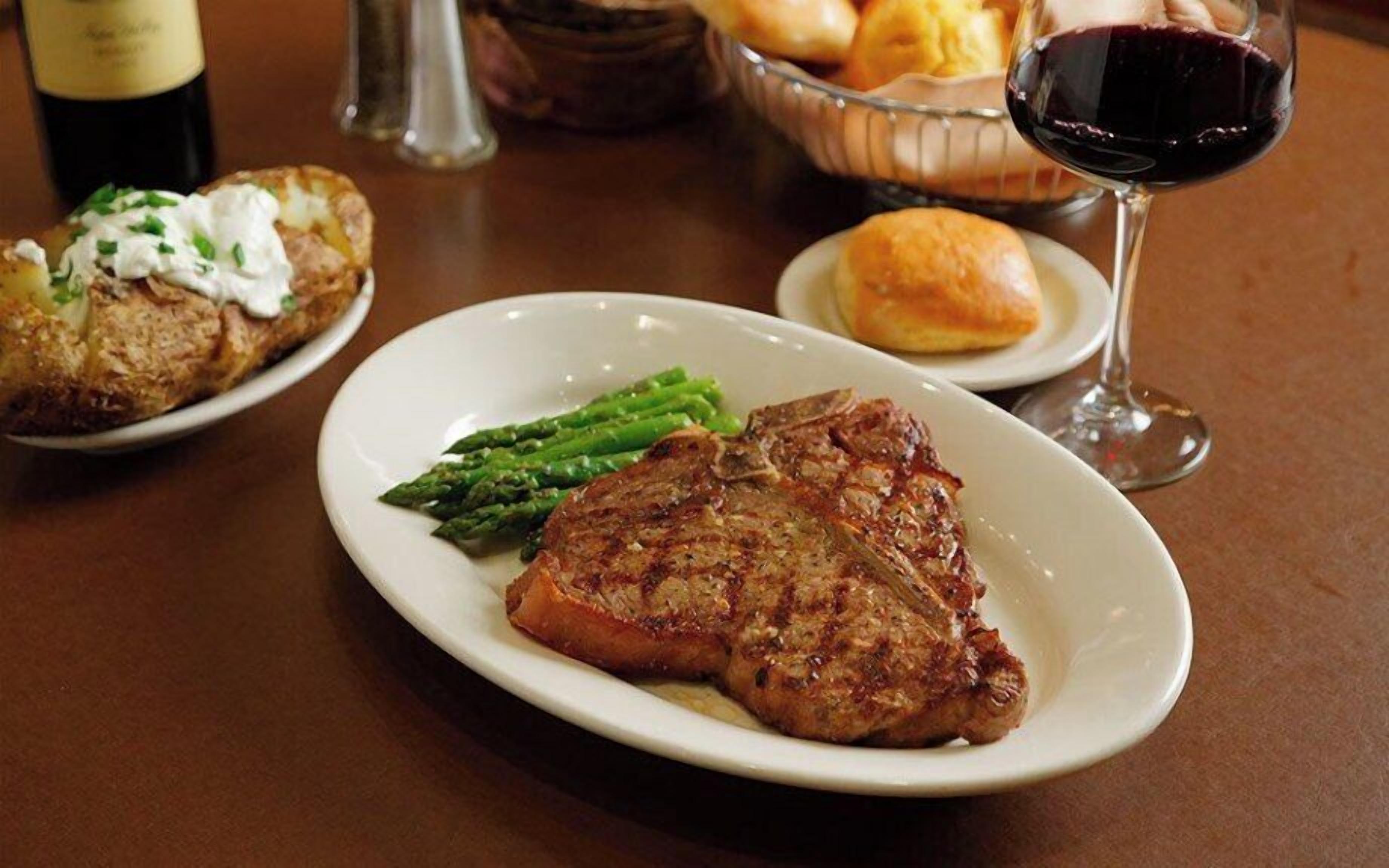 A plate with a steak, asparagus, and a side of potatoes.