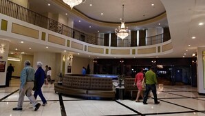 A spacious lobby with a grand chandelier, a round seating area, and a second-floor balcony.